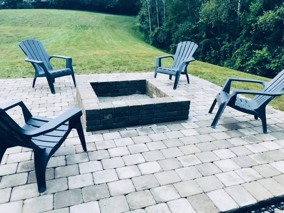 Custom interlock stone patio with built-in square brick firepit and Adirondack chairs