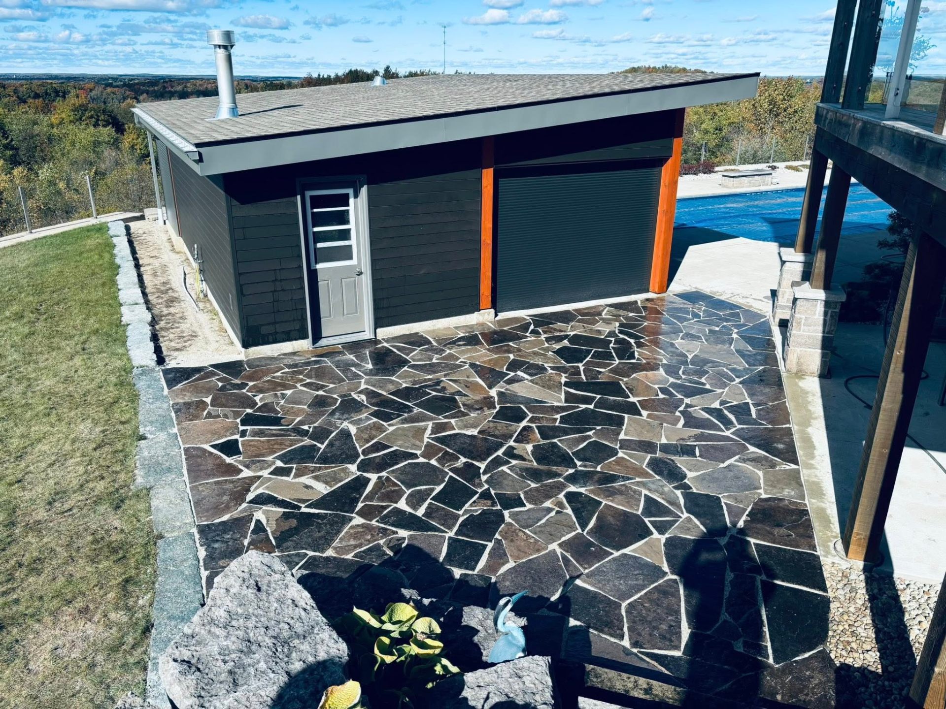 Custom flagstone patio installation beside a poolside cabana